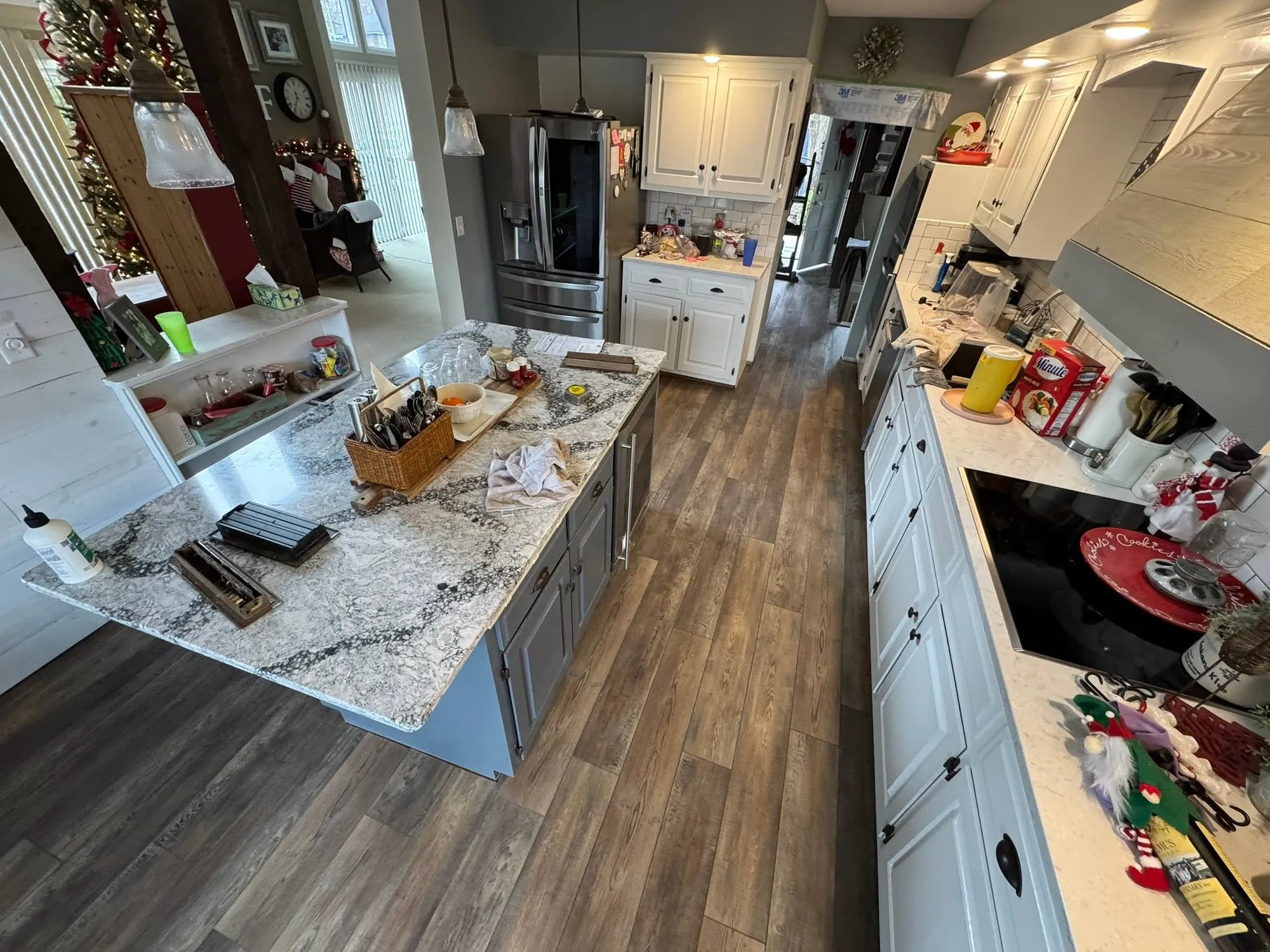 Kitchen with a granite island and newly installed dark plank flooring running the length of the room